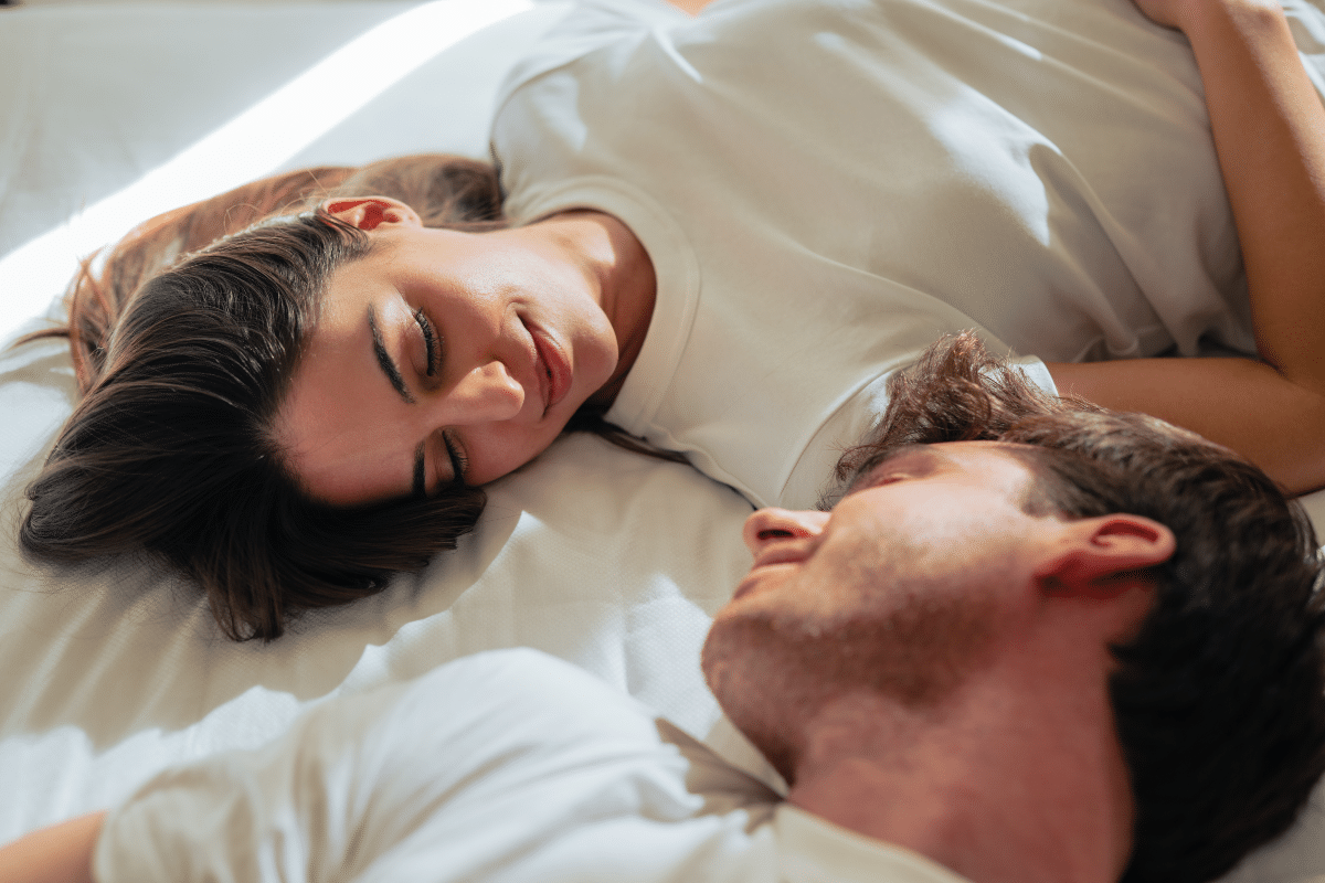 Young couple lying on a bed, gazing at each other in the morning light